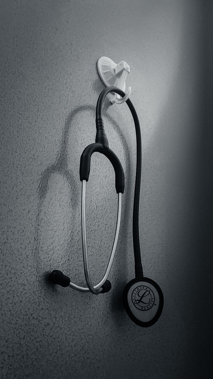 team-02 Monochrome image of a stethoscope hanging on a wall, conveying a medical theme.
