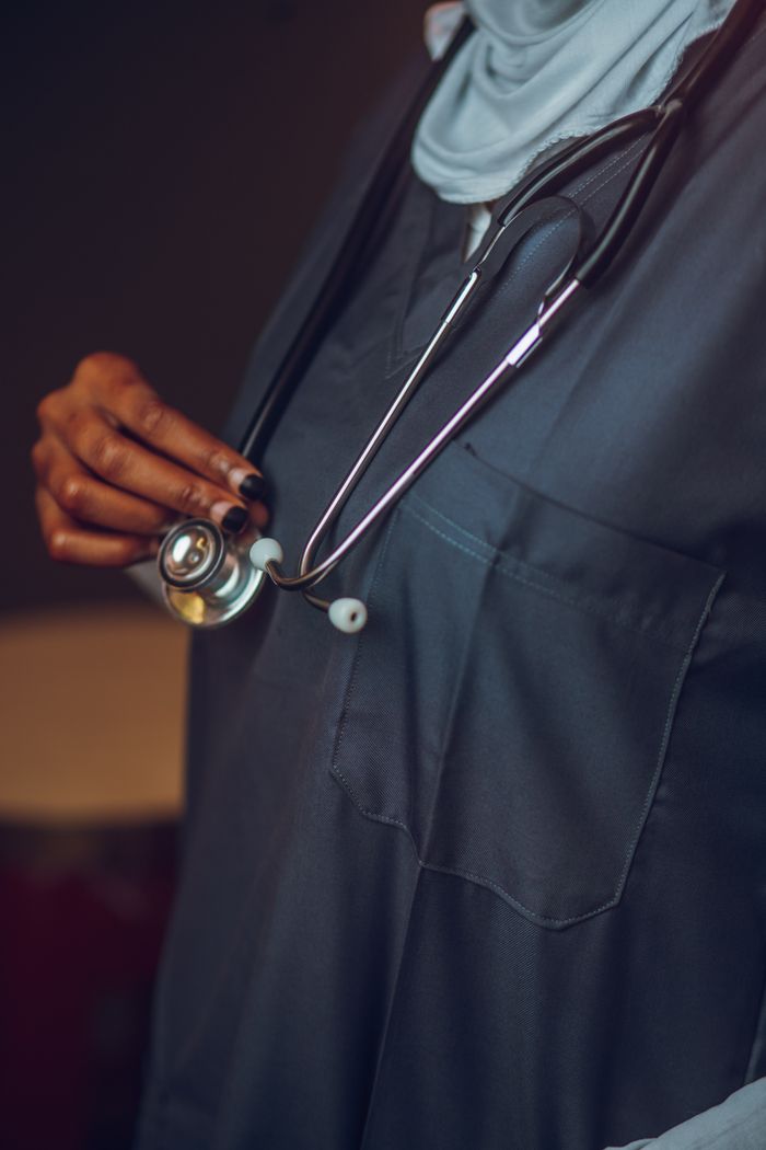 team-04 Close-up of a healthcare professional holding a stethoscope, focusing on medical attire and equipment.