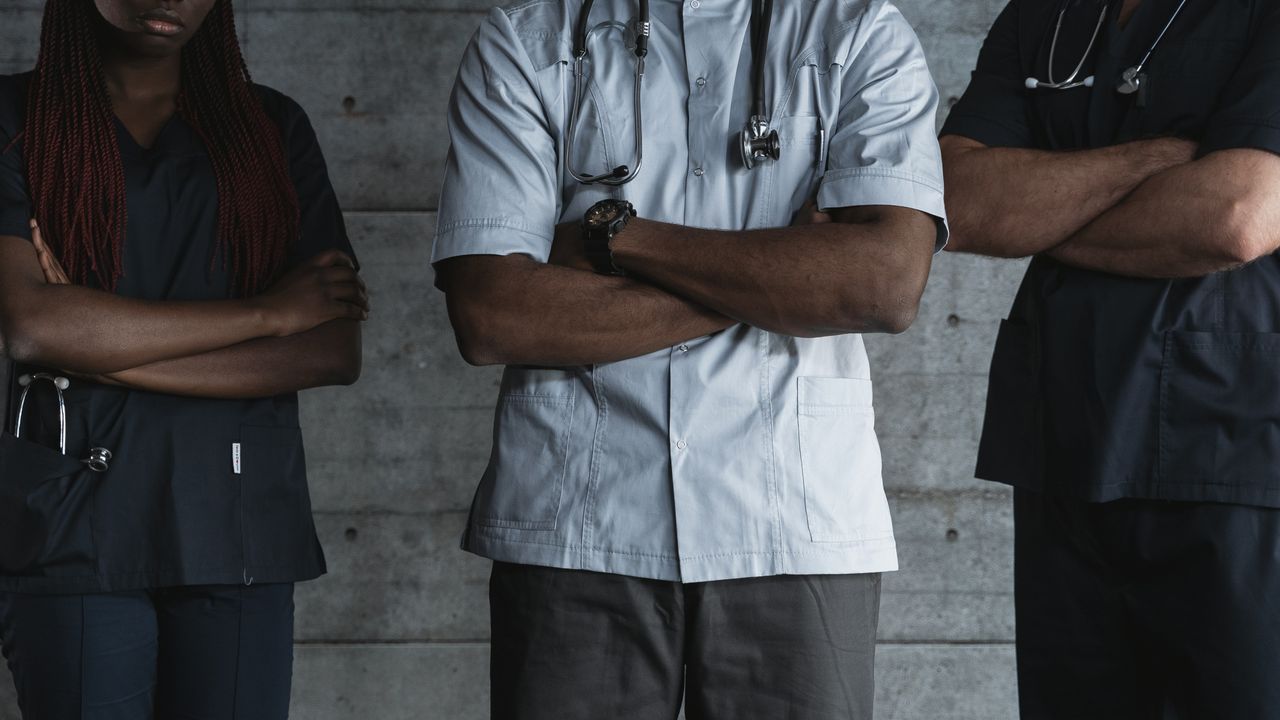 team-03 Group of medical professionals standing confidently with folded arms in uniform.